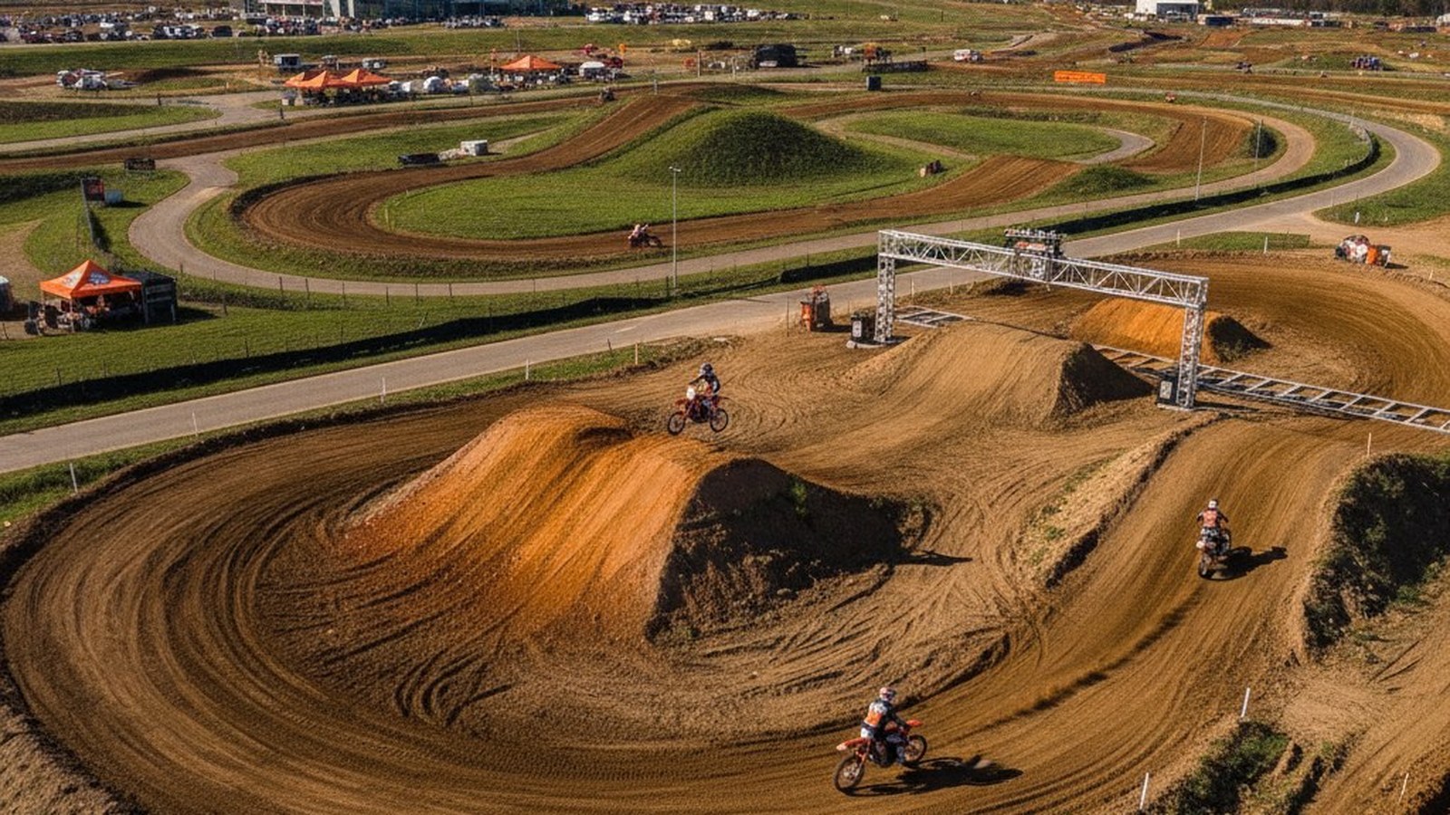 Aerial view of a professional outdoor motocross track with sculpted berms, jumps, and a full start gate